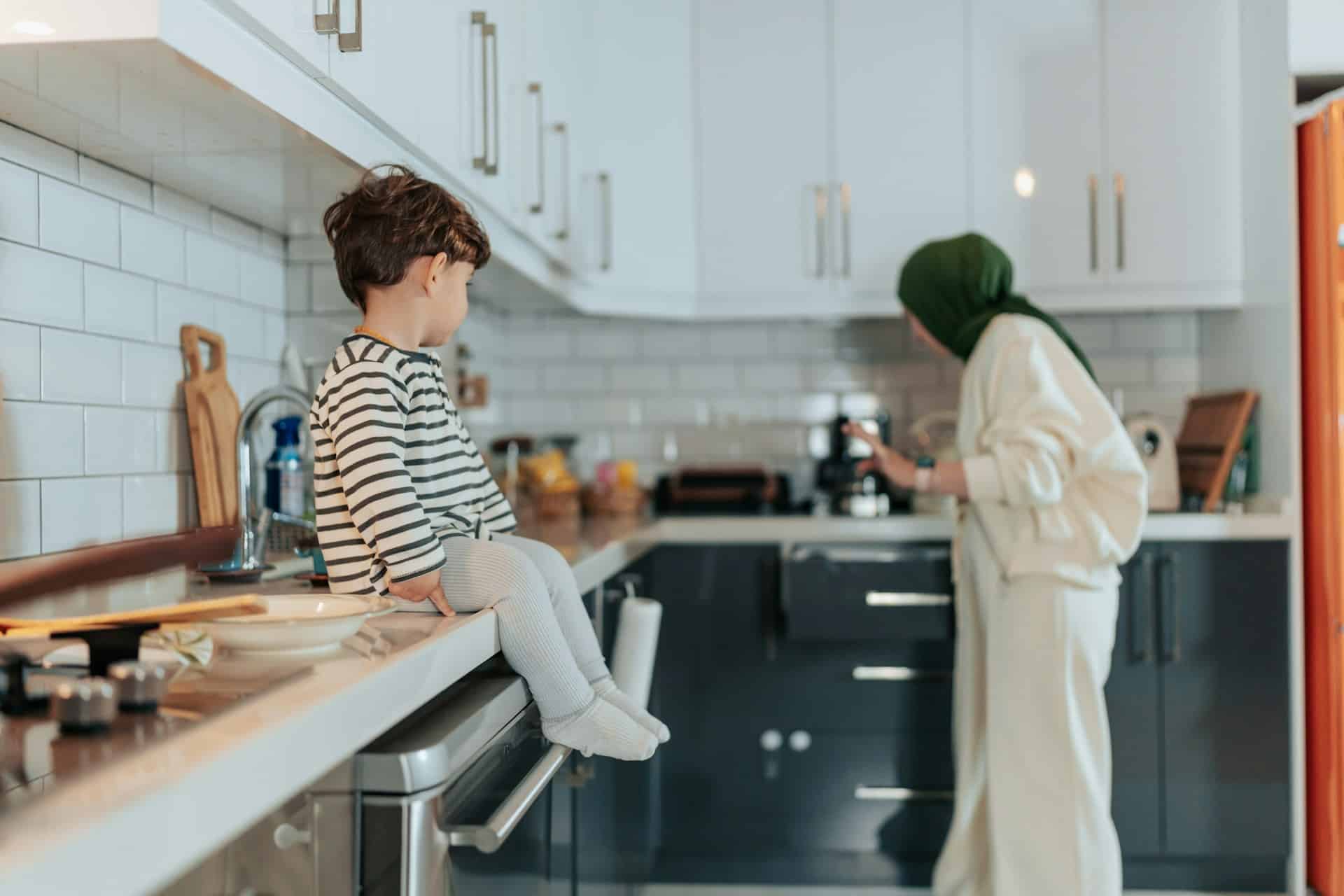 kid sitting on kitchen counter looking at adult